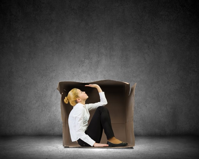 Young businesswoman sitting in carton box and feeling uncomfortable.jpeg